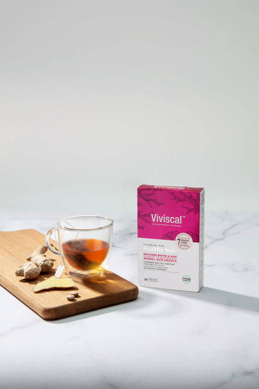 Healthy hair vitamins next to a cup of ginger herbal tea