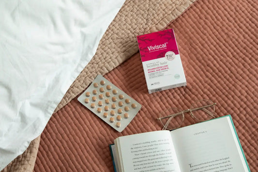 Healthy hair vitamins next to book and reading glasses